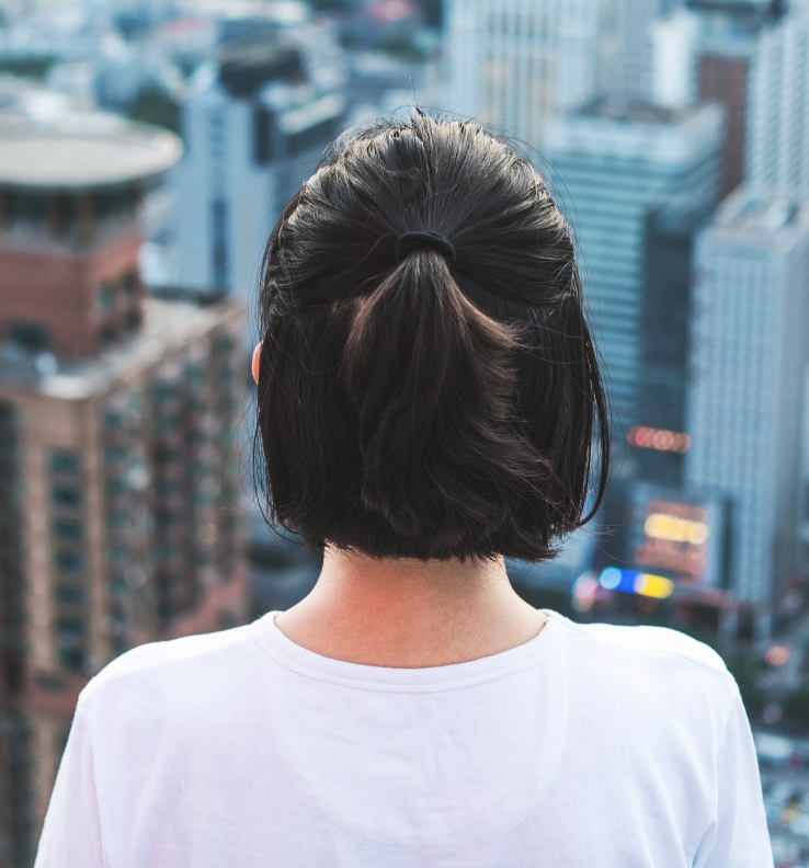 Young woman looks out over the city at the top of the building